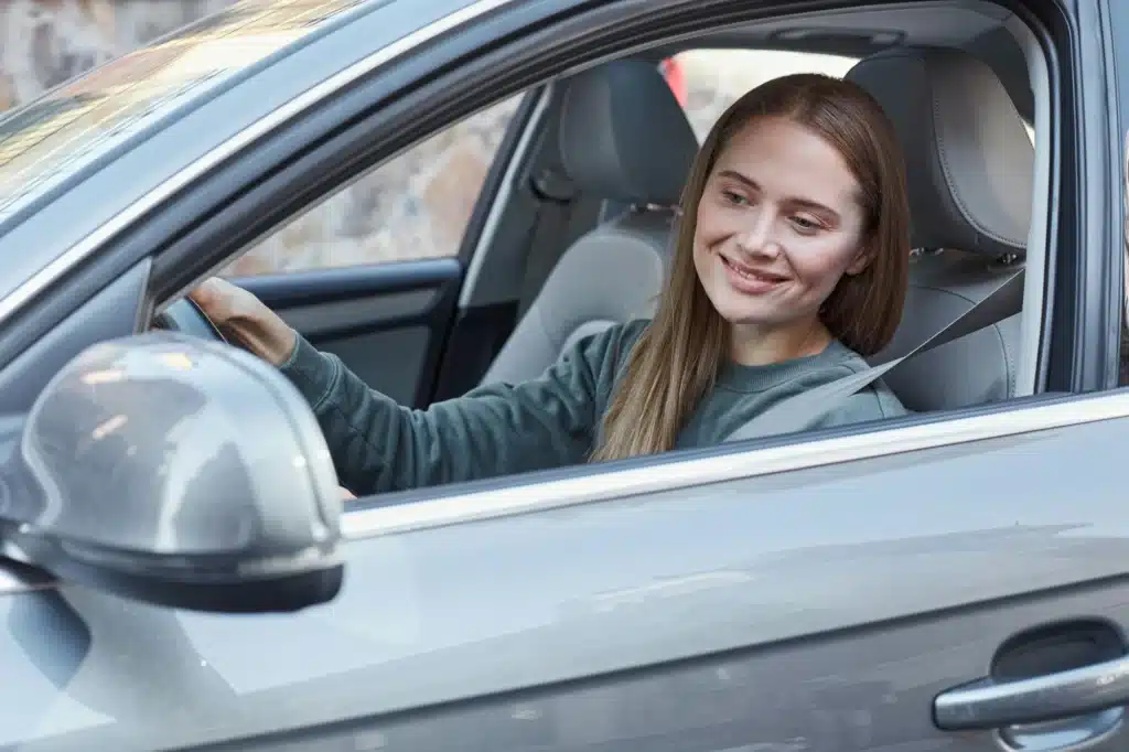 A person smiles and checks the side mirror of their car after fighting a ticket and winning in Calgary.