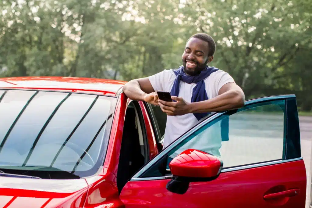 A person stands outside of their car, using their phone to look up the number of a traffic court expert in Calgary.