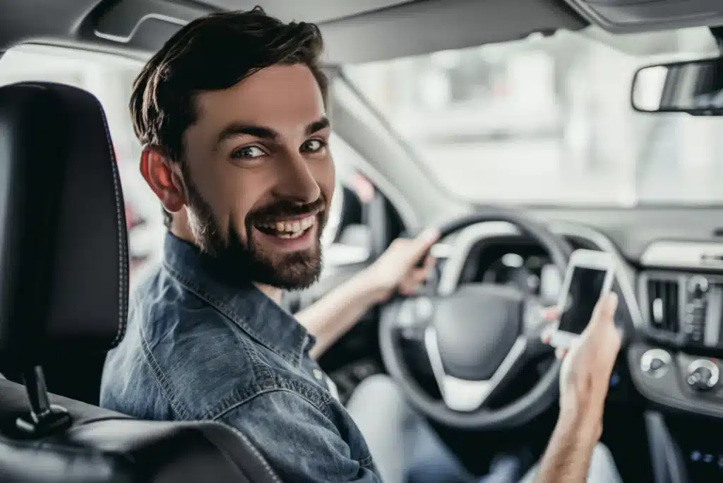 A person in a parked car smiles and looks behind them after making a call to a traffic ticket expert.