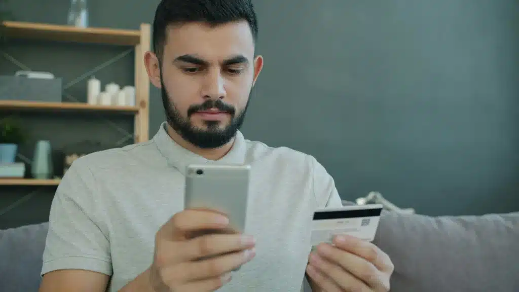 A person holds a credit card and pays a traffic ticket on their phone.