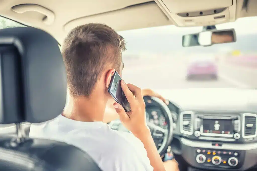 A person driving talks on their cell phone while switching lanes on a highway in Alberta.
